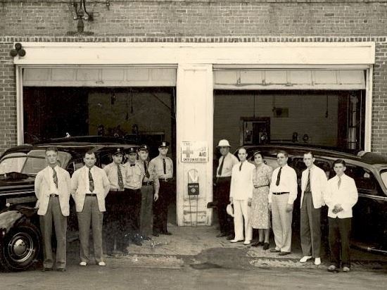 Old firefighters in front of cars