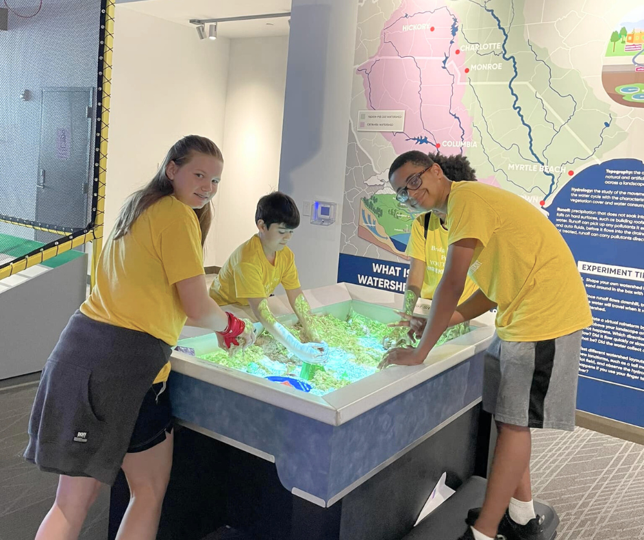 A group of children explore the topographic sand table at the Monroe Science Center.
